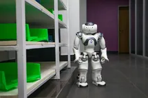 A humanoid robot next to a shelf with astonished face.