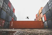 A photo of a big ship container with a person jumping on top.