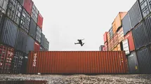 A photo of a big ship container with a person jumping on top.