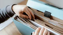 A photo of a person classifing documents into a paper documents folder.