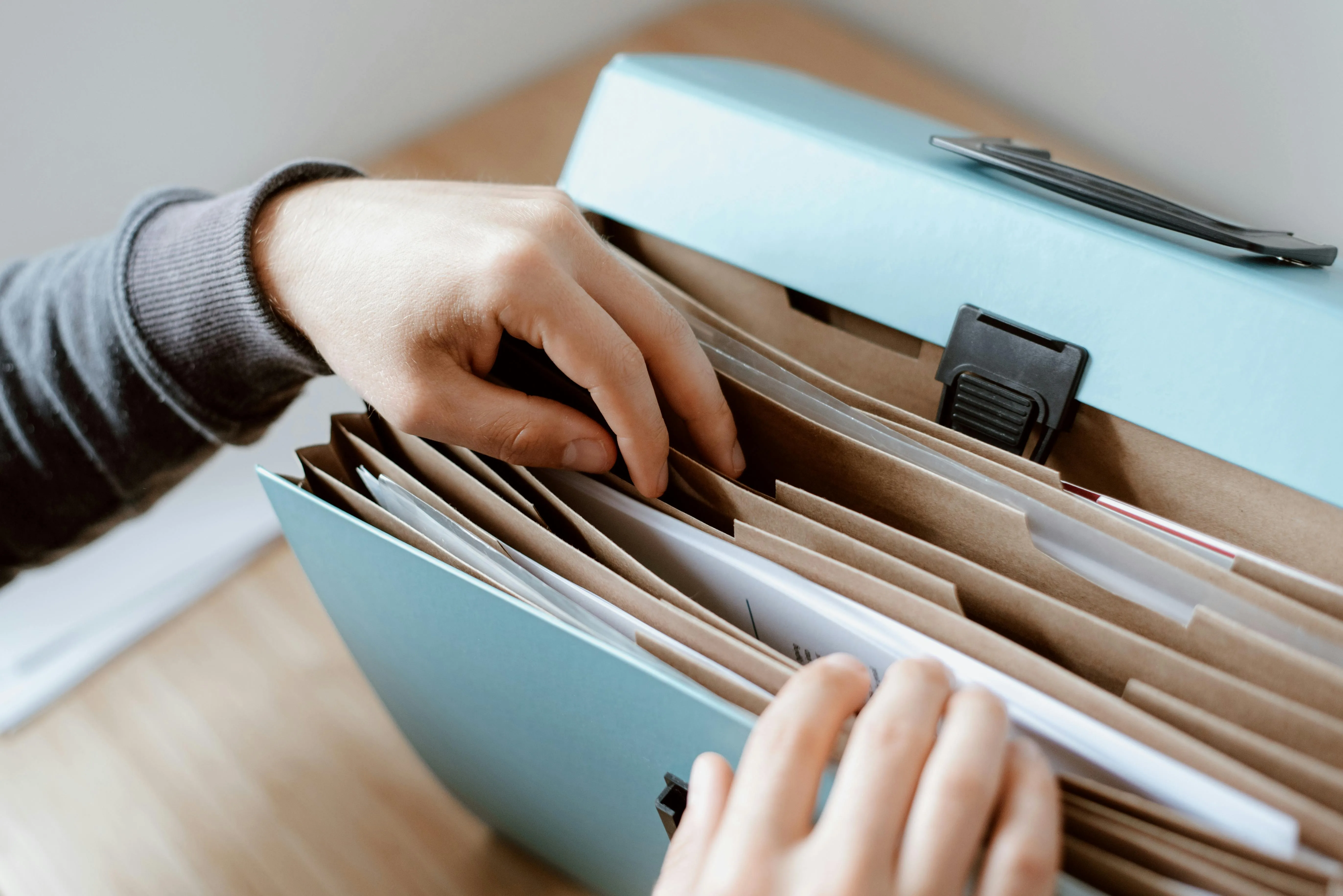 A photo of a person classifing documents into a paper documents folder.