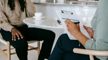 Job interview of a manger taking notes while sitting ona table taking coffee with the candidate.