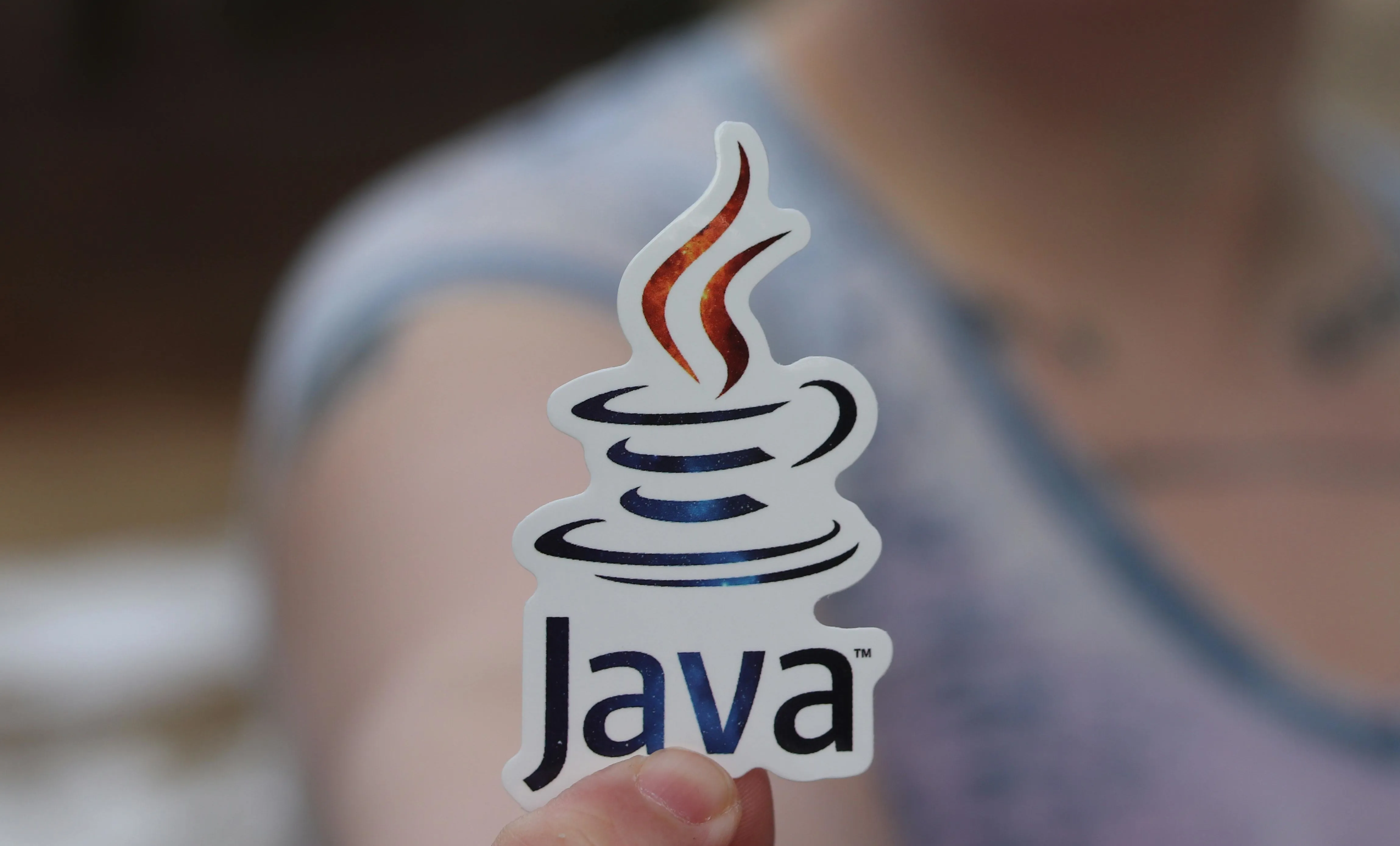 A woman on the background holding a java logo on her fingers.