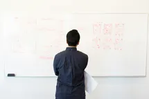 A photo of a guy looking at a whiteboard with a flowchart diagram