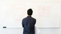 A photo of a guy looking at a whiteboard with a flowchart diagram