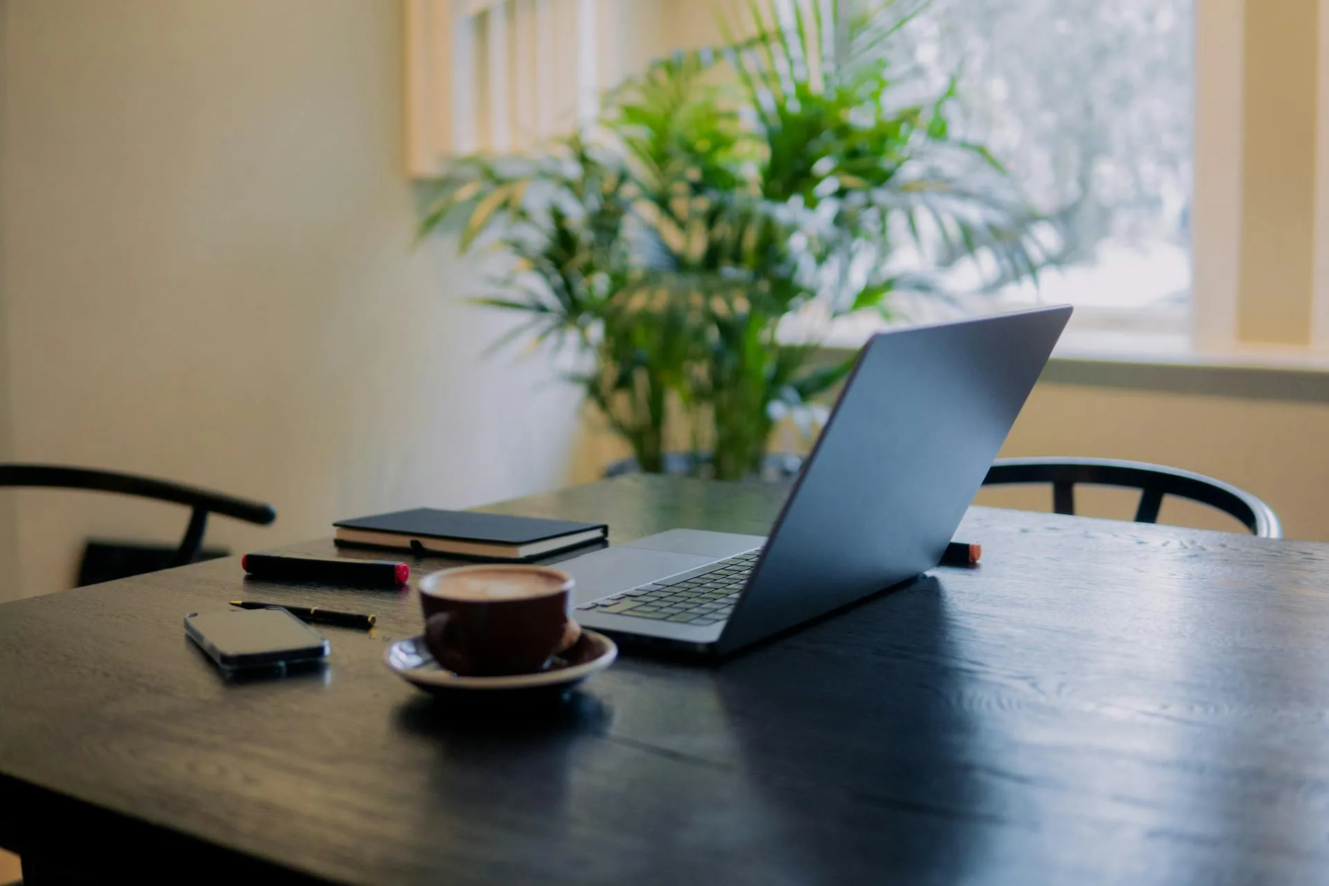 A photo of a remote work setup with a laptop on a table in a cafe