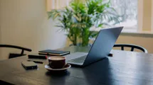 A photo of a remote work setup with a laptop on a table in a cafe