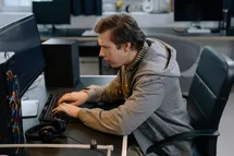 Software dev coding with confused face.