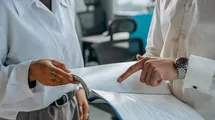 Two persons discussing about some content on a book.